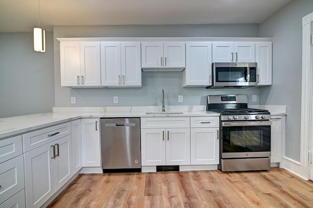 kitchen featuring a sink, light wood finished floors, white cabinetry, and stainless steel appliances