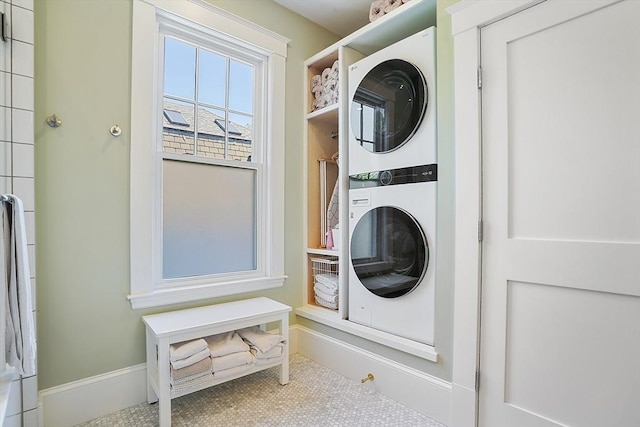 washroom featuring baseboards and stacked washing maching and dryer