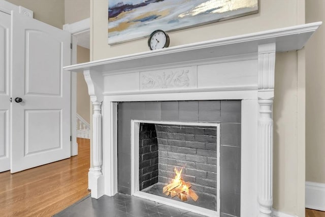 room details featuring a tiled fireplace and hardwood / wood-style flooring