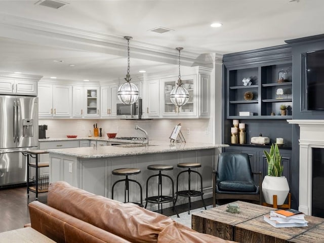 115 Sewall Ave Unit 1, Brookline, MA 02446 - kitchen with appliances with stainless steel finishes, white cabinets, a kitchen bar, hanging light fixtures, and light stone countertops