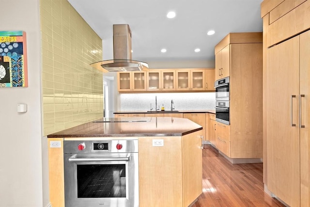 26 Saxon Rd, Newton, MA 02461 - kitchen featuring light brown cabinetry, island exhaust hood, light wood finished floors, glass insert cabinets, and stovetop