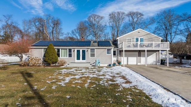 view of front of property with a garage, a front yard, french doors, and solar panels