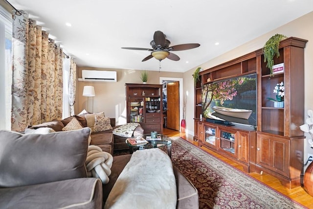 living room featuring ceiling fan, light hardwood / wood-style floors, and an AC wall unit