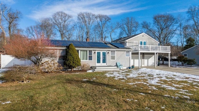 view of front of home featuring a garage, a lawn, french doors, and solar panels