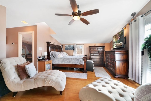 bedroom with ceiling fan, vaulted ceiling, and light wood-type flooring