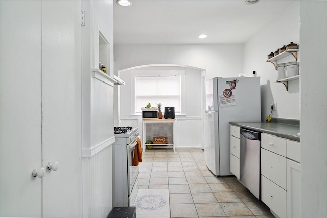 139 Washington St, Hudson, MA 01749 - kitchen with white appliances, open shelves, light tile patterned floors, dark countertops, and arched walkways
