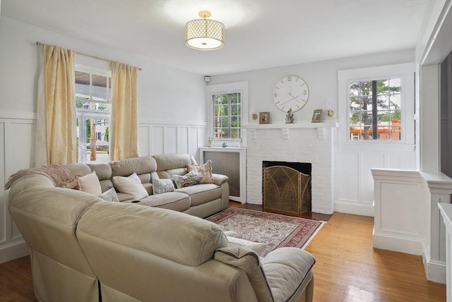 139 Washington St, Hudson, MA 01749 - living area featuring a decorative wall, wainscoting, a brick fireplace, and light wood-style flooring