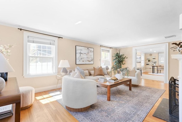 living room featuring visible vents, light wood-style flooring, baseboards, and a fireplace