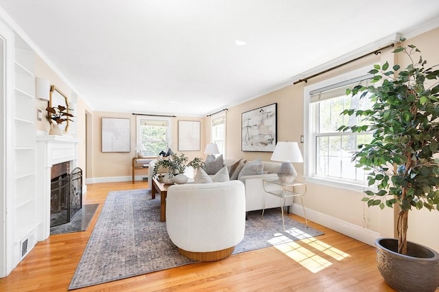 living area with visible vents, a fireplace with flush hearth, light wood finished floors, and baseboards