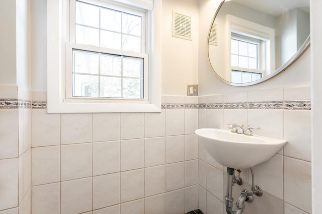 bathroom with visible vents, a wainscoted wall, and tile walls