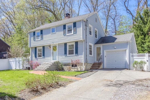 colonial-style house featuring an attached garage, driveway, a chimney, and entry steps