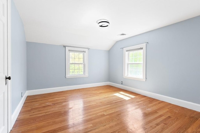 additional living space with visible vents, lofted ceiling, light wood finished floors, and a wealth of natural light