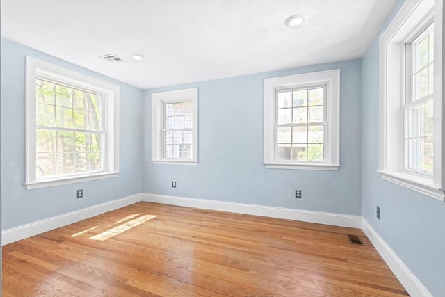 unfurnished room with light wood-style floors, baseboards, and visible vents
