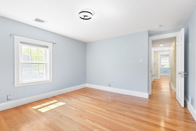 empty room with baseboards, a healthy amount of sunlight, and light wood-style flooring