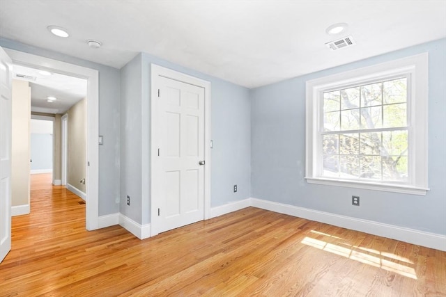 unfurnished bedroom with a closet, baseboards, visible vents, and light wood-type flooring