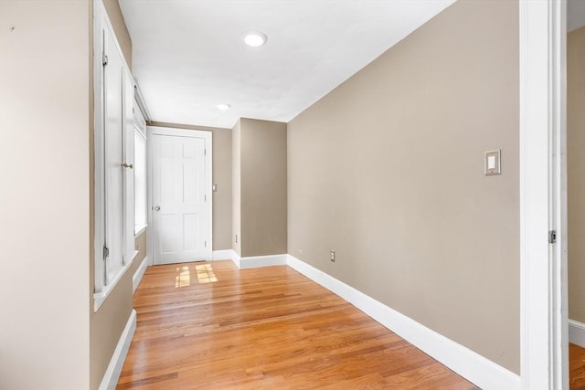 empty room featuring recessed lighting, baseboards, and light wood finished floors