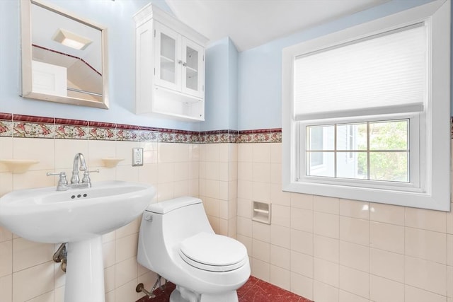 half bathroom with tile walls, wainscoting, and toilet