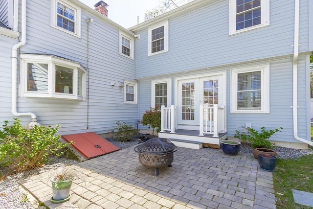rear view of property featuring french doors, a chimney, a patio area, and an outdoor fire pit