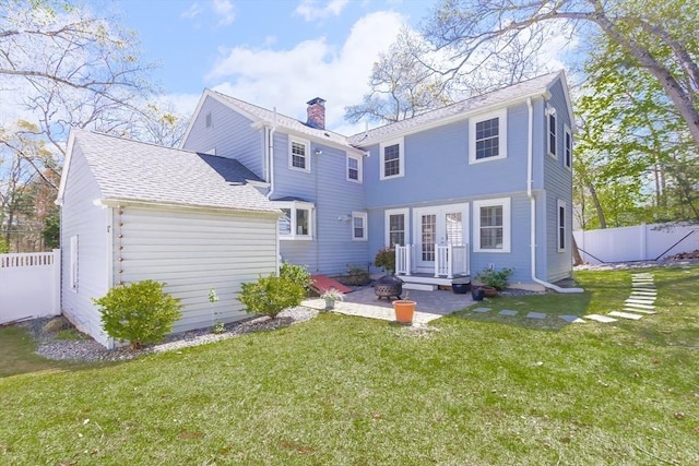 back of property with fence, a chimney, a shingled roof, a patio area, and a yard