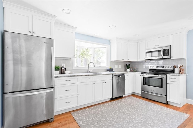kitchen with a sink, white cabinetry, decorative backsplash, and stainless steel appliances