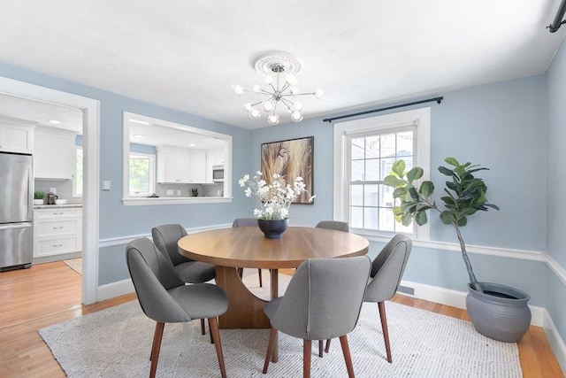 dining space featuring baseboards, an inviting chandelier, and light wood-style flooring
