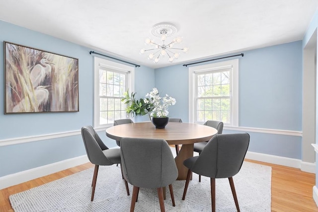 dining area featuring light wood-style floors, a healthy amount of sunlight, baseboards, and a notable chandelier
