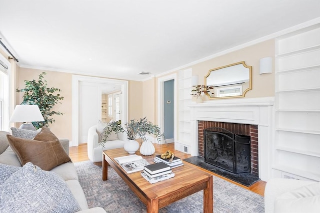 living room featuring a brick fireplace, visible vents, built in features, and wood finished floors