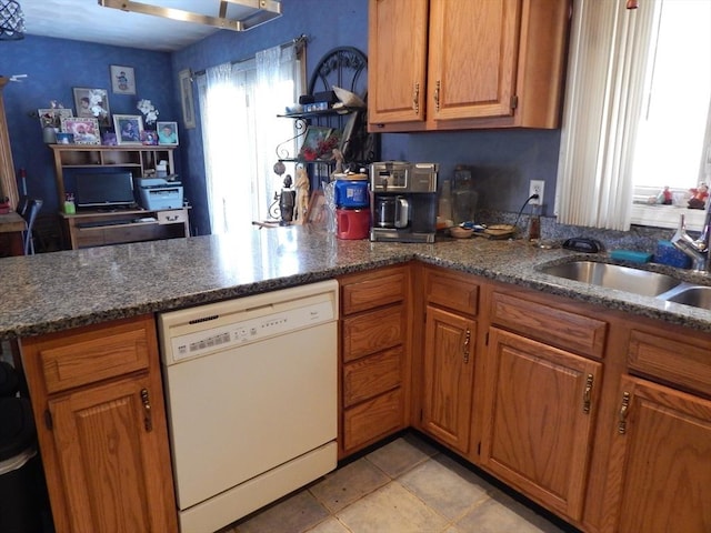 13 Lark St, New Bedford, MA 02745 - kitchen with a sink, a peninsula, brown cabinetry, dark stone countertops, and white dishwasher