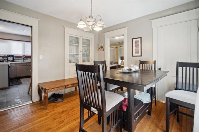 dining space featuring sink, light wood-type flooring, and an inviting chandelier