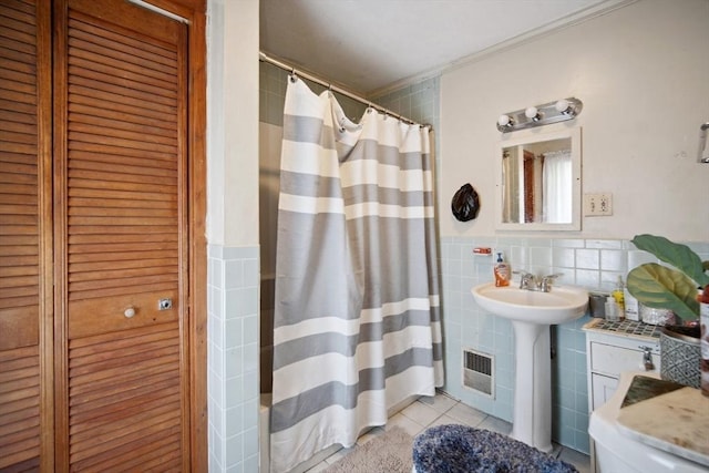 bathroom with curtained shower, tile walls, tile patterned flooring, sink, and ornamental molding