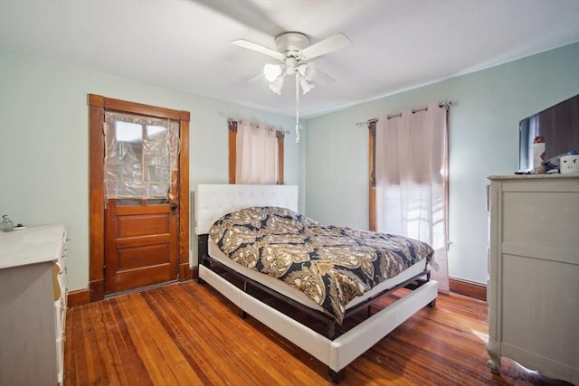 bedroom featuring ceiling fan, dark wood-type flooring, and multiple windows