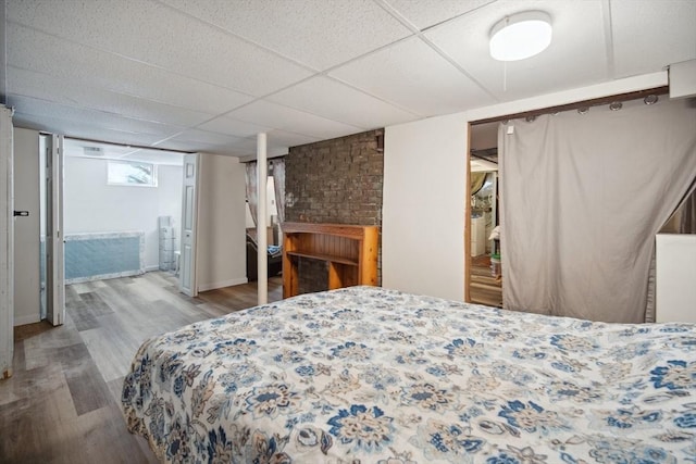 bedroom with light wood-type flooring and a drop ceiling