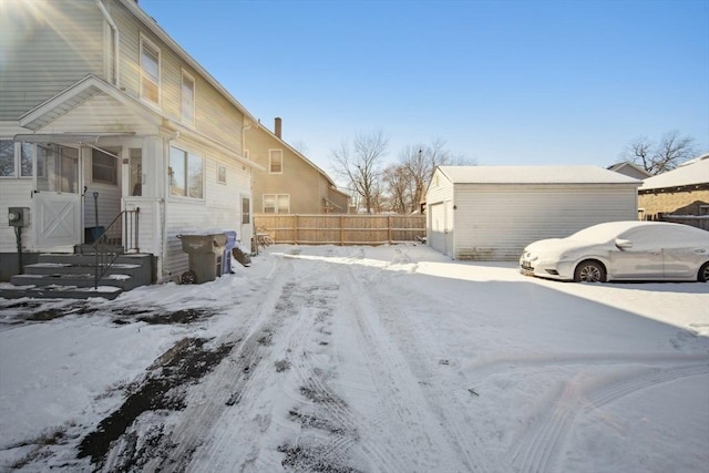 view of snowy exterior with a garage and an outdoor structure