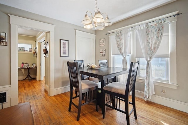 dining area with light hardwood / wood-style floors and a notable chandelier