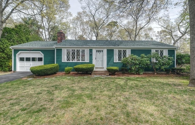 ranch-style house featuring an attached garage, a chimney, asphalt driveway, and a front yard
