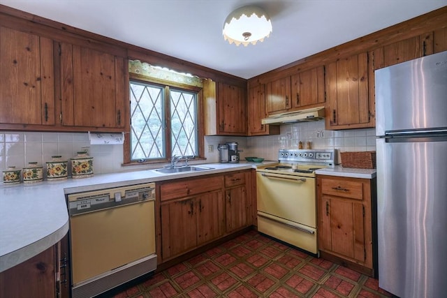 kitchen featuring freestanding refrigerator, dishwasher, white electric stove, under cabinet range hood, and a sink