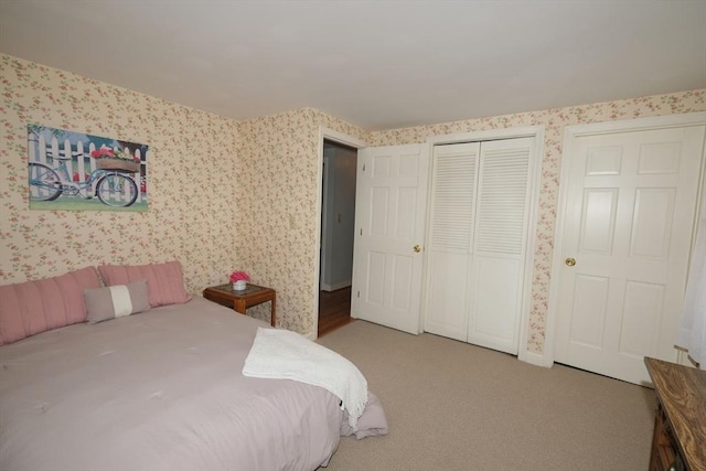 bedroom with wallpapered walls, carpet, and a closet
