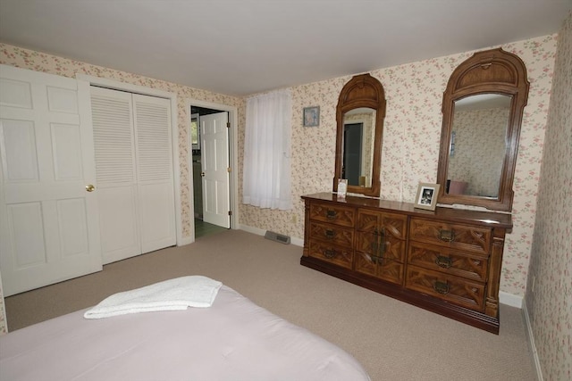 carpeted bedroom with wallpapered walls, baseboards, and a closet
