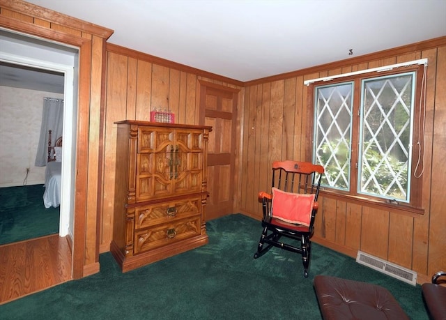 sitting room featuring carpet floors, wooden walls, and ornamental molding