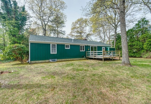 rear view of house featuring a wooden deck, a lawn, and board and batten siding