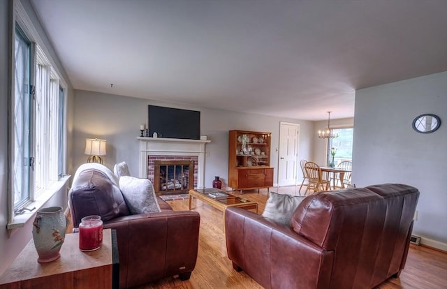 living room with a chandelier, wood finished floors, and a fireplace