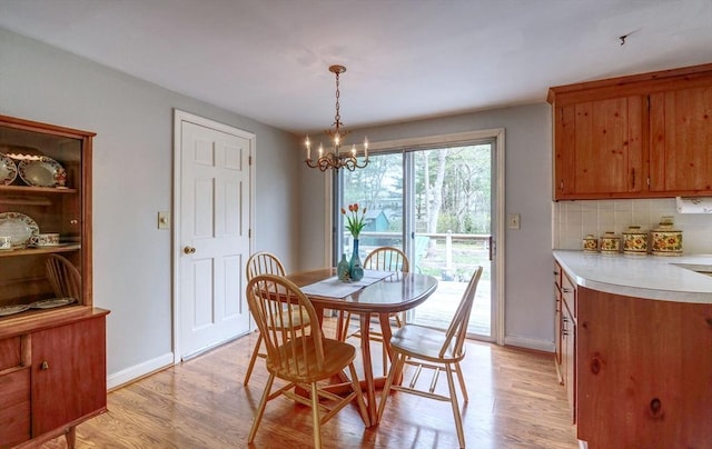 dining room with light wood-type flooring, a chandelier, and baseboards