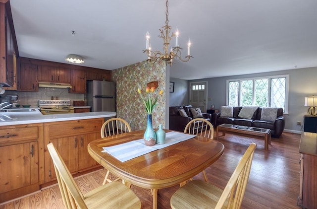 dining area featuring a chandelier, light wood-type flooring, and baseboards
