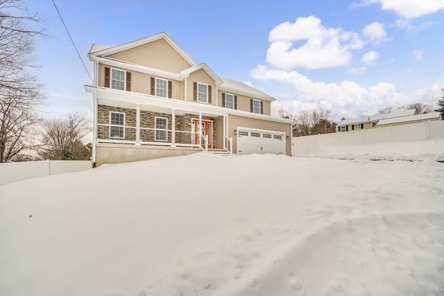 traditional-style home with a porch, stone siding, fence, and an attached garage