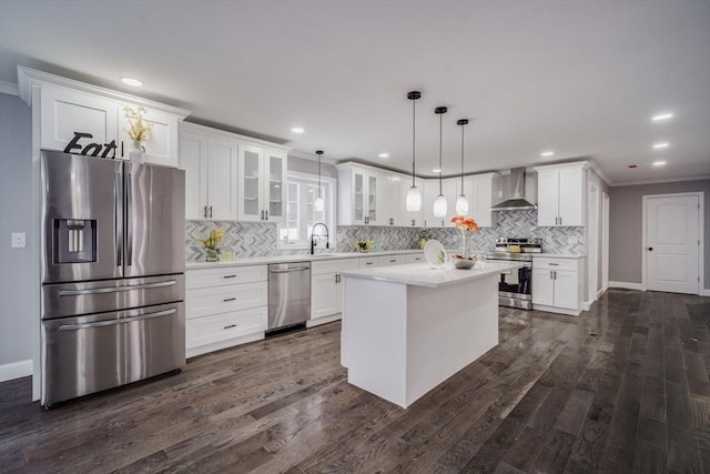 kitchen featuring glass insert cabinets, appliances with stainless steel finishes, light countertops, wall chimney range hood, and pendant lighting