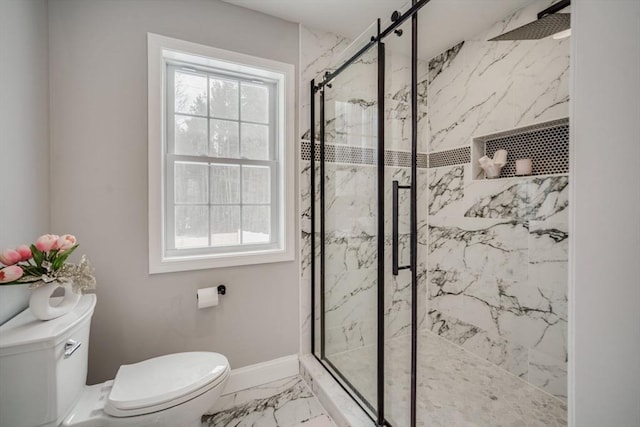 bathroom featuring toilet, marble finish floor, a marble finish shower, and baseboards