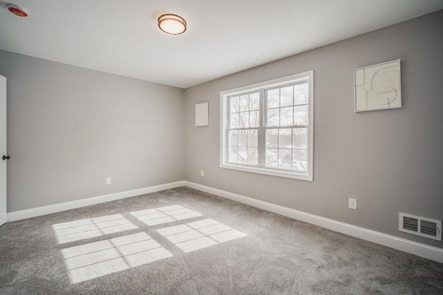 carpeted spare room featuring visible vents and baseboards