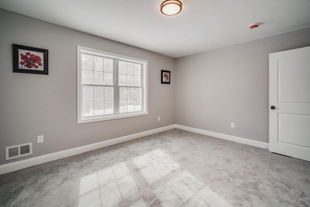 empty room featuring visible vents, light carpet, and baseboards