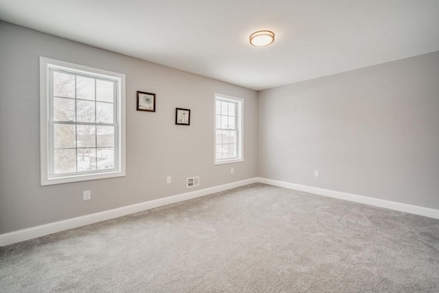 carpeted spare room featuring visible vents and baseboards