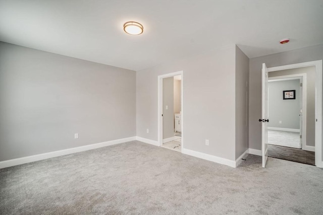 unfurnished bedroom featuring ensuite bath, baseboards, and light colored carpet